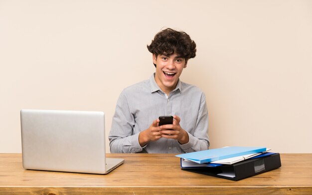 Uomo giovane studente con un laptop sorpreso e l'invio di un messaggio