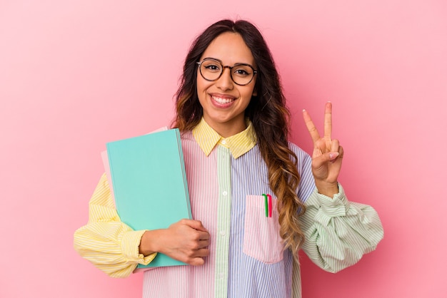 Young student mexican woman isolated on pink background showing number two with fingers.