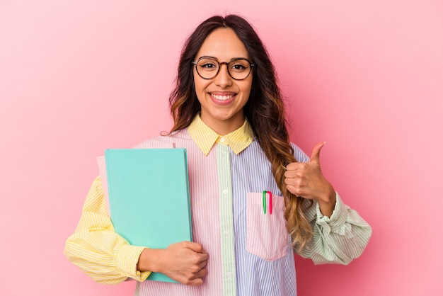 Young student mexican woman isolated on pink background smiling and raising thumb up