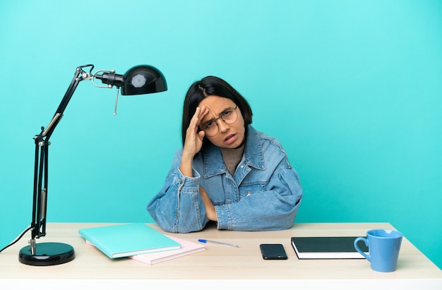 Young student mixed race woman studying on a table looking far away with hand to look something