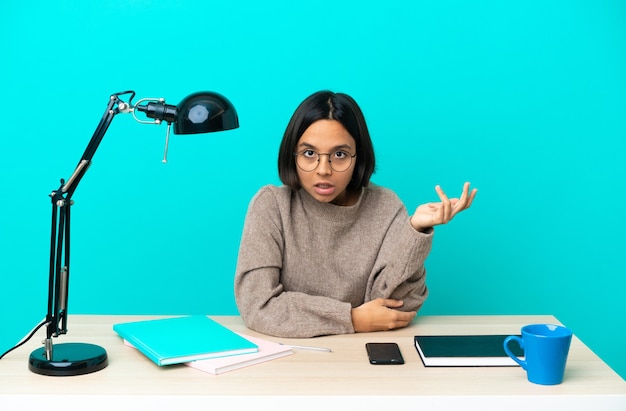 Young student mixed race woman studying on a table making doubts gesture