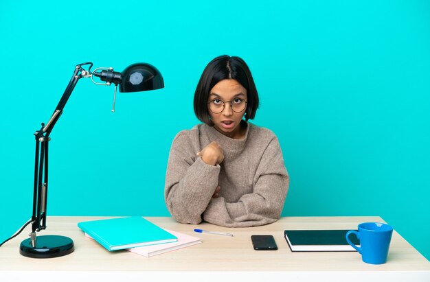 Young student mixed race woman studying on a table pointing to oneself