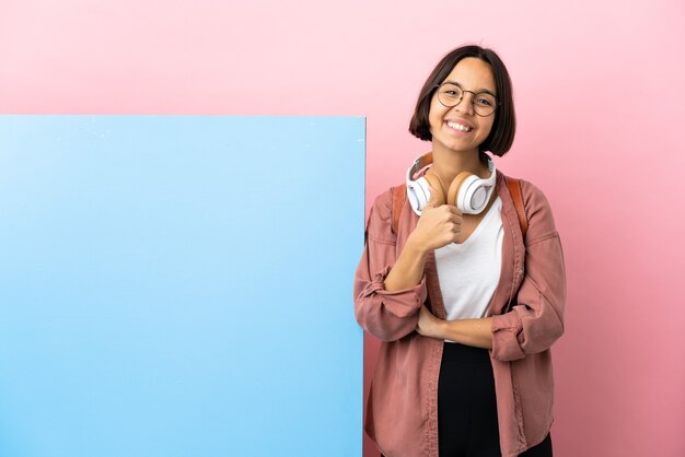 Young student mixed race woman with a big banner over isolated background giving a thumbs up gesture