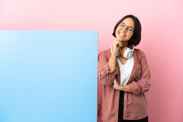 Young student mixed race woman with a big banner isolated background laughing