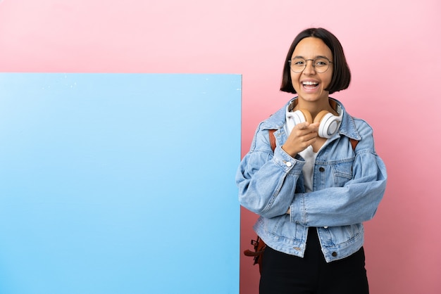 Young student mixed race woman with a big banner over isolated background surprised and pointing front