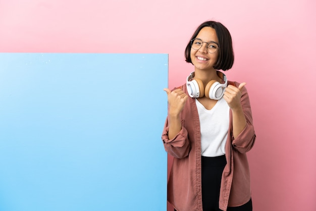 Young student mixed race woman with a big banner over isolated background with thumbs up gesture and smiling