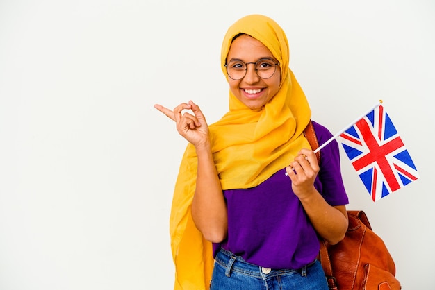 Young student muslim woman isolated on white background smiling and pointing aside, showing something at blank space.