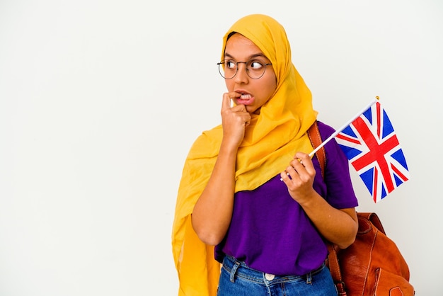 Young student muslim woman isolated on white wall relaxed thinking about something looking at a copy space