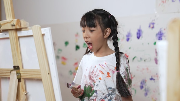 芸術のレッスンで塗装された壁にキャンバスを描いた若い学生