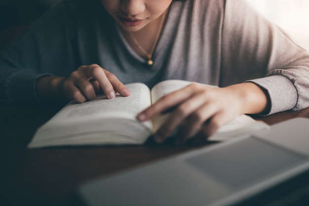 Giovane studente che legge libro tailandese alla biblioteca pubblica.