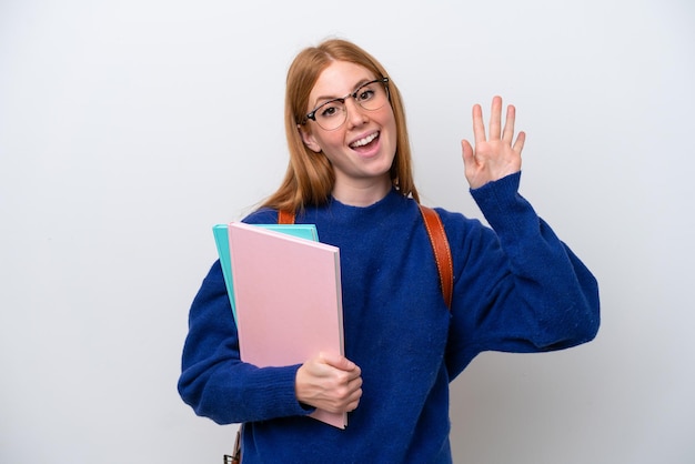 幸せな表情で手で敬礼する白い背景で隔離の若い学生赤毛の女性