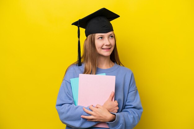 Young student Russian woman isolated on yellow background thinking an idea while looking up