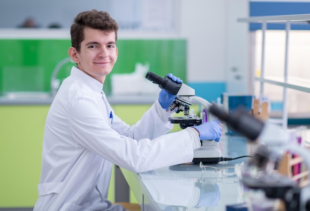 Young student scientist looking through a microscope while doing some research in the laboratory