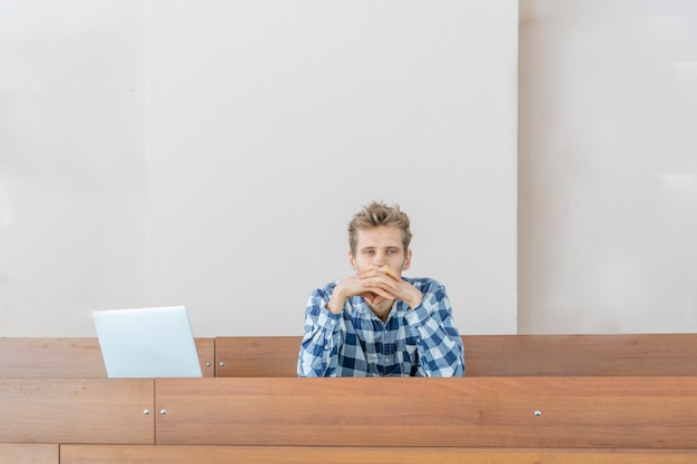 Young student sit alone in huge lecture hall