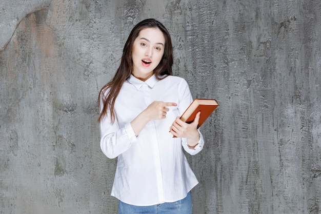 Young student or teacher in white shirt holding book. High quality photo