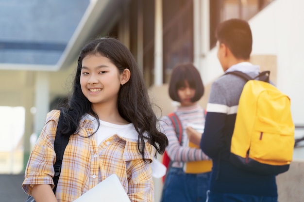 사진 백그라운드에서 친구와 함께 schoolbag 지주 노트북을 들고 젊은 학생 십 대 소녀 고등학교 학생