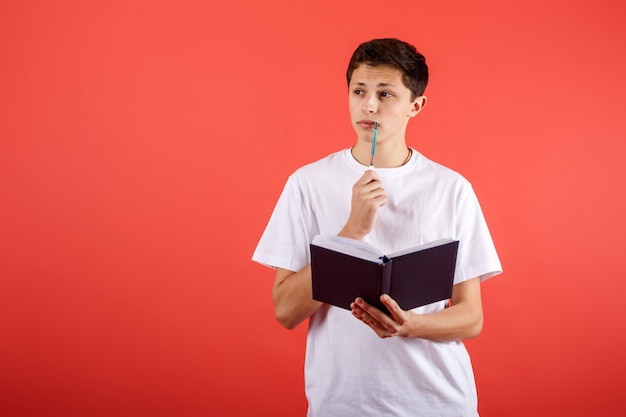 Young student thinking and holding a notebook and pen