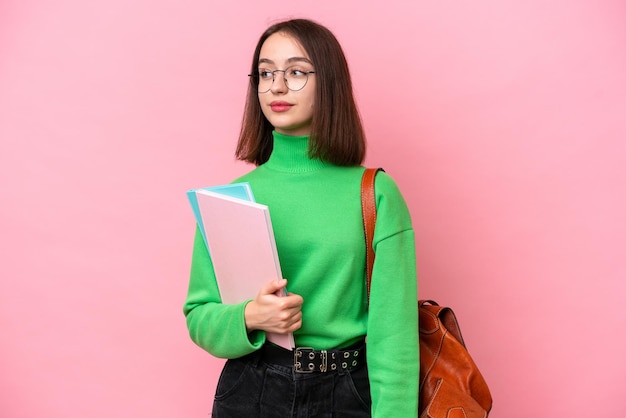 Young student Ukrainian woman isolated on pink background looking to the side