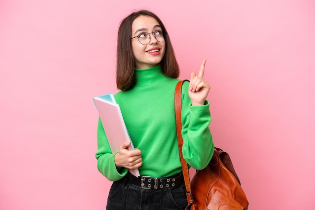 Young student Ukrainian woman isolated on pink background pointing up a great idea