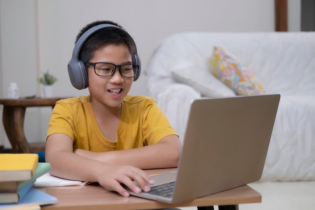 Молодой студент используя компьютер изучая онлайн.