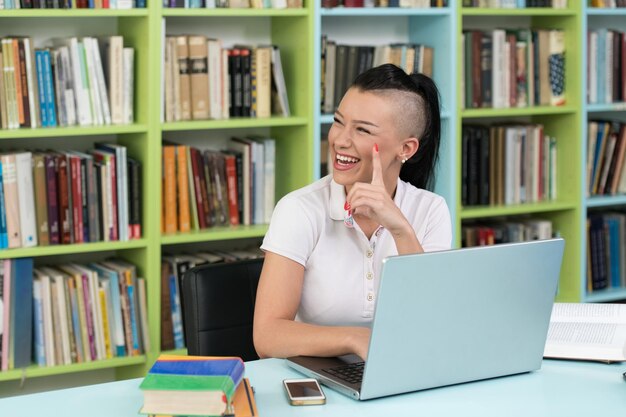 Photo young student using her laptop in a library