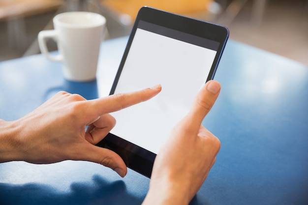 Young student using his tablet in cafe