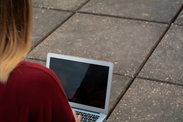 Молодой студент, используя ноутбук на открытом воздухе.