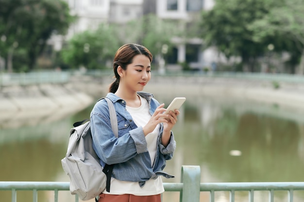 公園でスマートフォンを使用して若い学生