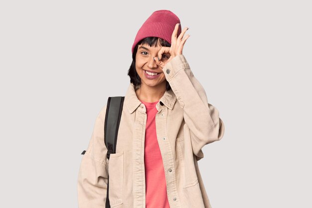 Photo young student with backpack and beanie in studio joyful and carefree showing a peace symbol