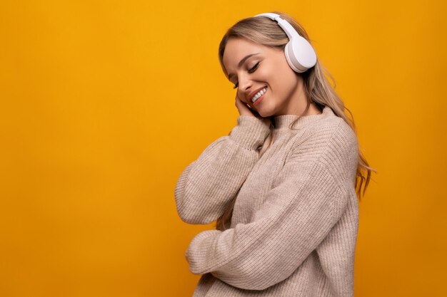 Young student with big headphones among yellow studio background