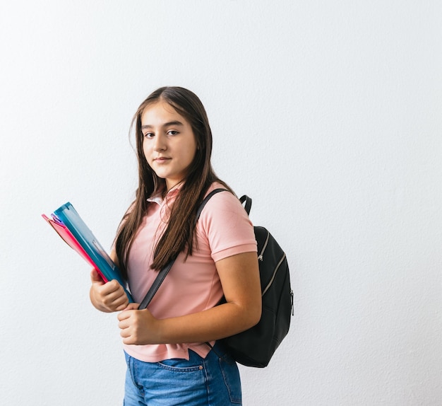 カラフルなフォルダーを持つ若い学生がカメラを見ています。