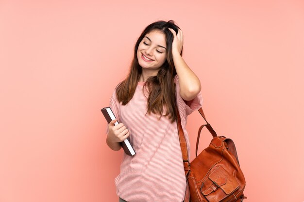 Young student woman going to the university over pink laughing