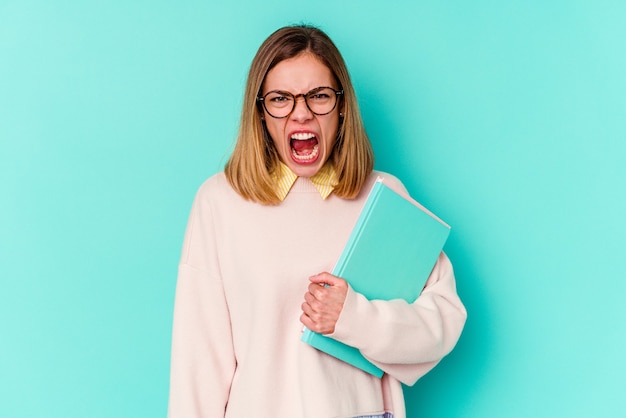 Young student woman holding books  screaming very angry and aggressive.