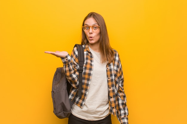 Young student woman holding something on palm hand