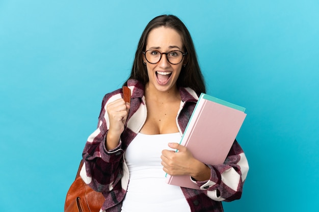 Young student woman over isolated background celebrating a victory in winner position