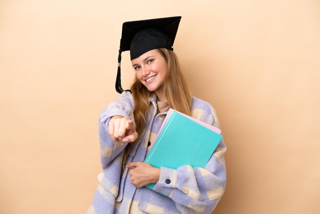 Young student woman over isolated background pointing front with happy expression