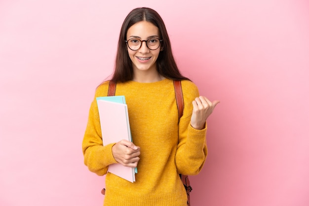 Young student woman over isolated background pointing to the side to present a product