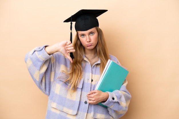 Young student woman over isolated background showing thumb down with negative expression