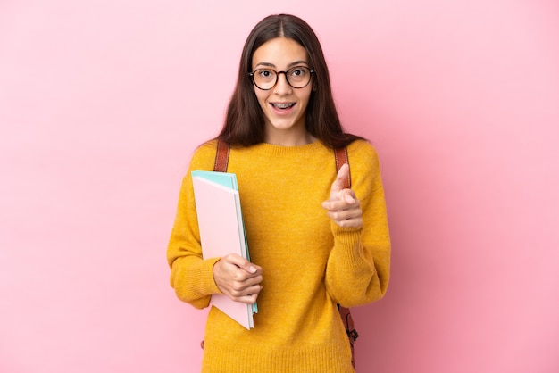 Young student woman over isolated background surprised and pointing front