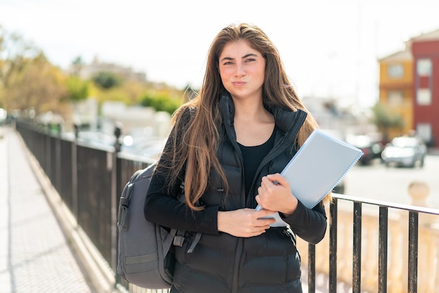 悲しい表情で孤立した背景の上の若い学生女性