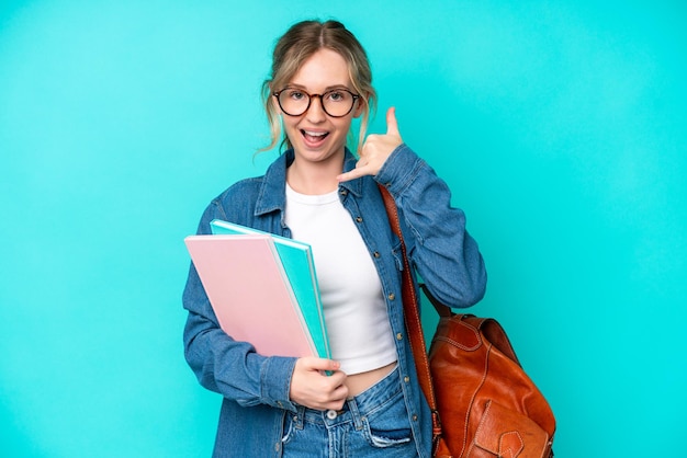 Young student woman isolated on blue background making phone\
gesture call me back sign