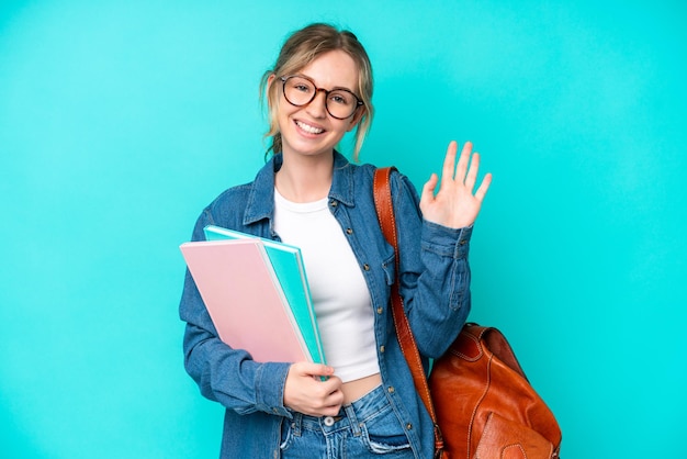 幸せな表情で手で敬礼青の背景に分離された若い学生の女性