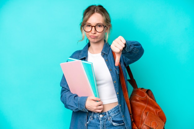 Young student woman isolated on blue background showing thumb down with negative expression