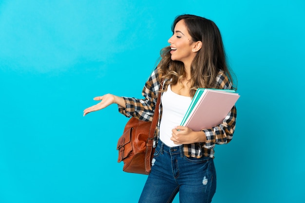 Young student woman isolated on blue background with surprise expression while looking side