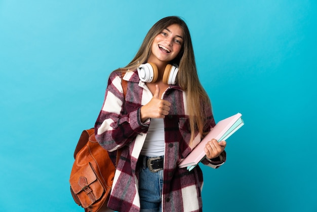 Young student woman isolated on blue giving a thumbs up gesture