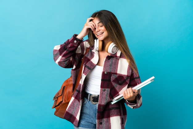 Young student woman isolated on blue laughing