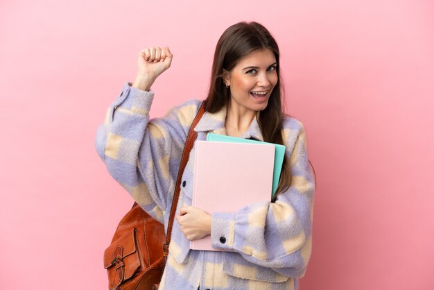 勝利を祝うピンクの背景に孤立した若い学生女性