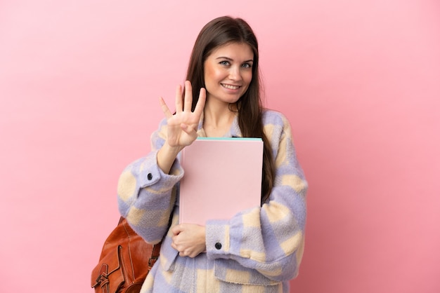 Молодая студентка женщина изолирована на розовом фоне счастлива и считает четыре пальцами