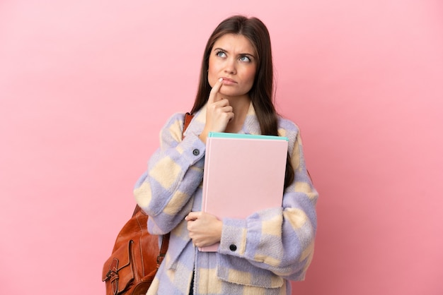 Young student woman isolated on pink background having doubts while looking up