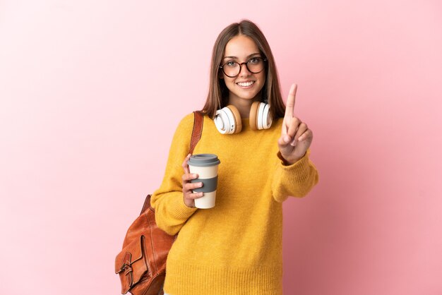 Young student woman over isolated pink background showing and lifting a finger